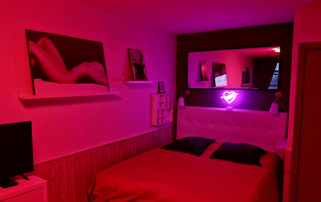 - une chambre rose dotée d'un lit avec lumière cardiaque dans l'établissement Village naturiste Beach Place, au Cap d'Agde