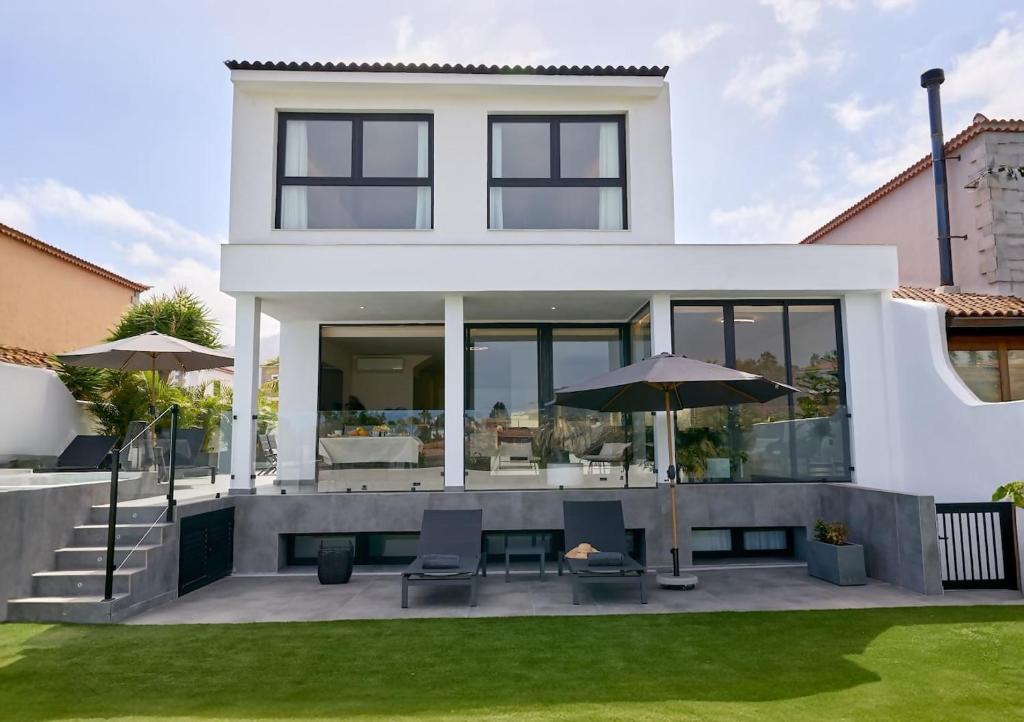 a white house with a patio with chairs and umbrellas at Casa Carlos in Puerto de la Cruz