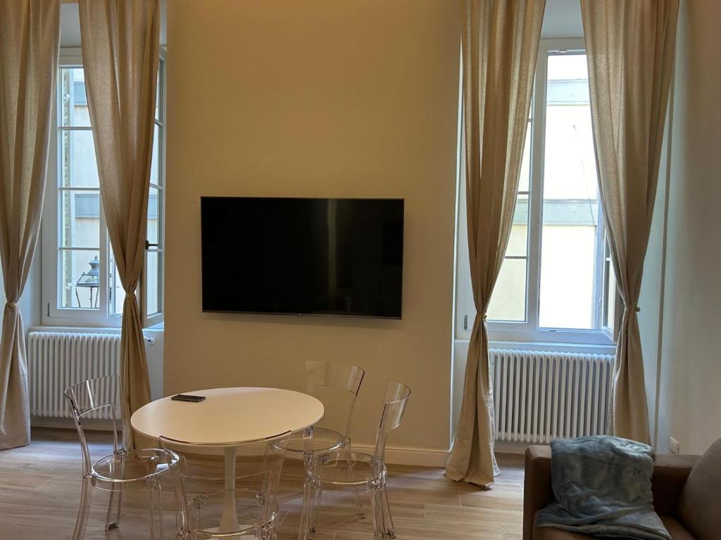 a living room with a table and chairs and a tv at Les Suites di Parma - Cavour in Parma