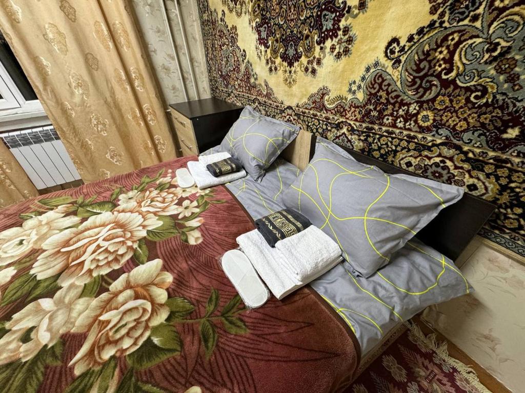1 dormitorio con cama con almohadas y manta en Nuri, en Karakol