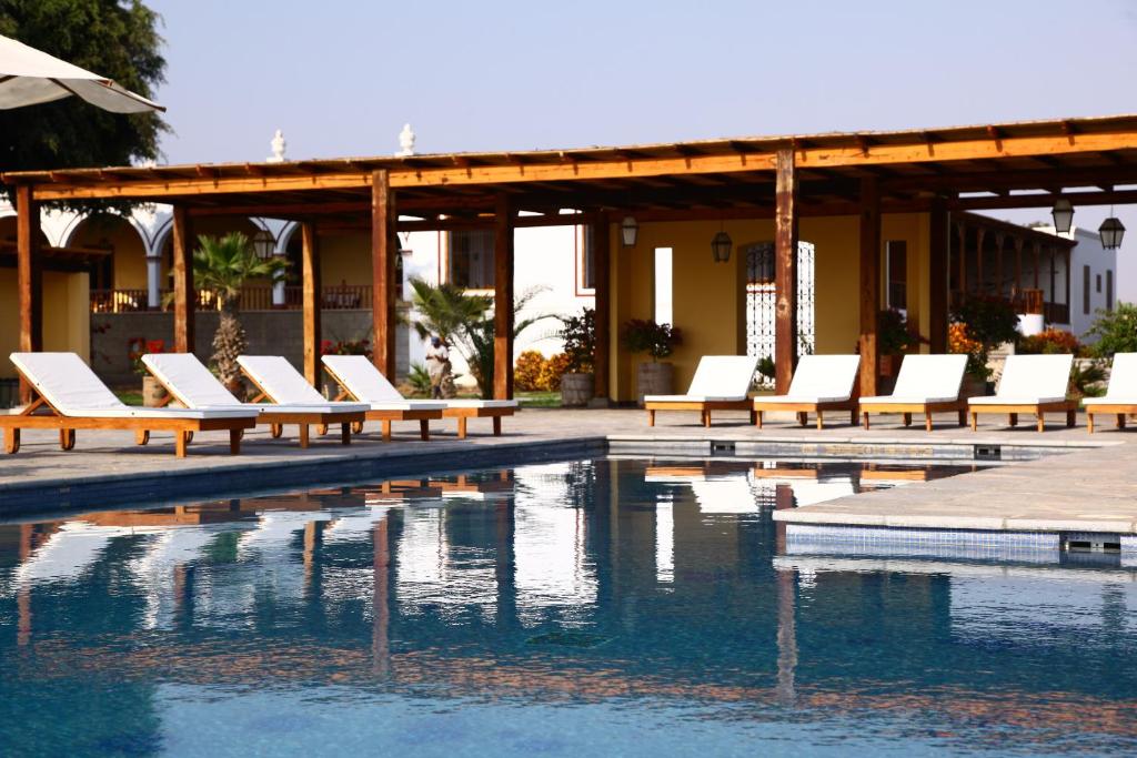 上欽查的住宿－卡薩哈斯恩達桑吉斯酒店，一组白色躺椅,位于游泳池旁