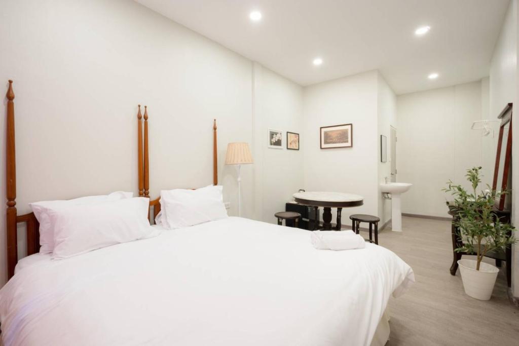 a white bedroom with a large bed and a table at Hidden Dragon China Town MRT Dragon Temple in Samphanthawong