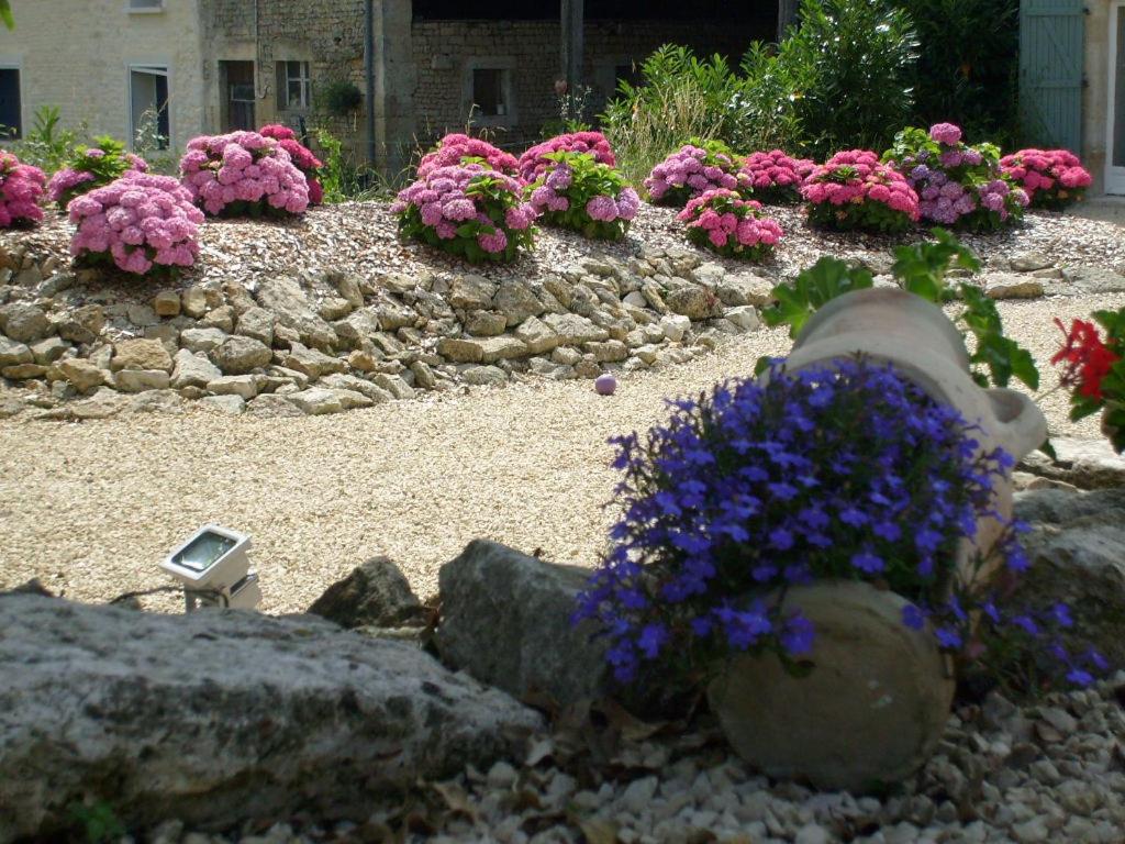 a garden with pink and purple flowers and rocks at La Grange de Gournay in  Gournay-Loizé