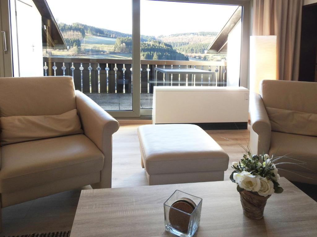 Una sala de estar con dos sillas y una mesa de café. en FeWo Pieck mit Parkplatz und privater Garage, en Winterberg