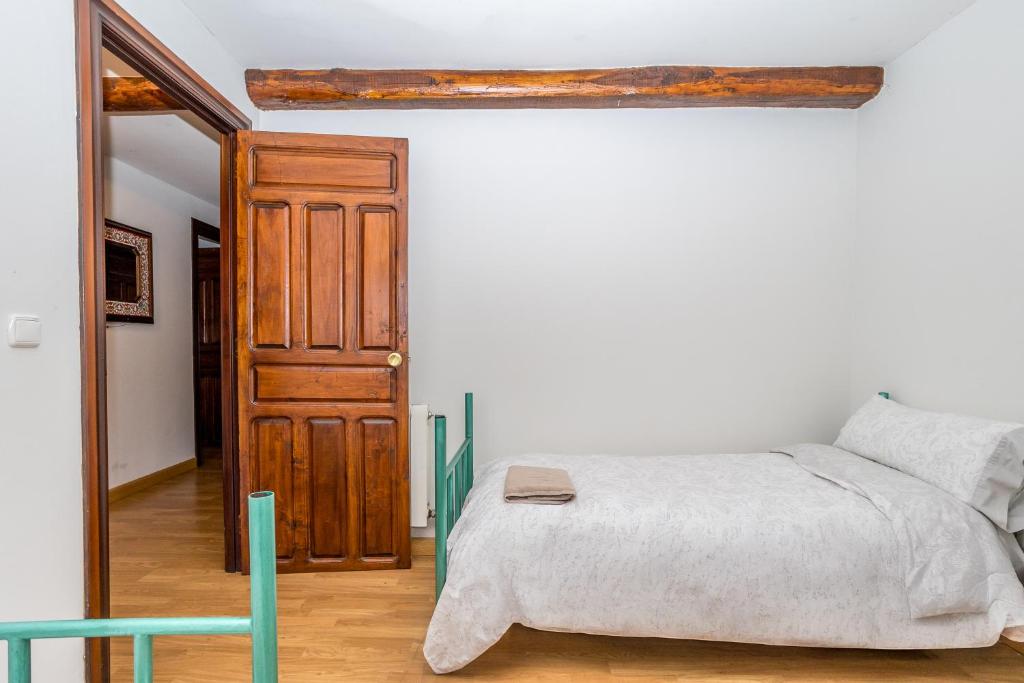 Un dormitorio con una cama y una puerta de madera. en BaruHaus VillaHermosa, en Villamañán