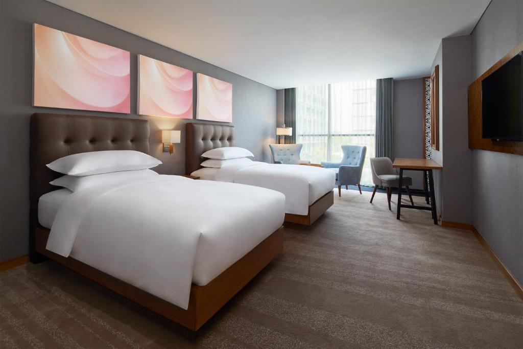 a hotel room with two beds and a desk at Four Points by Sheraton Balikpapan in Balikpapan