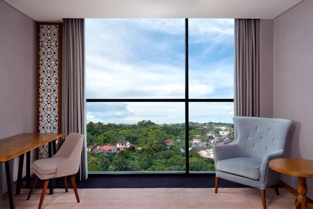 a room with two chairs and a large window at Four Points by Sheraton Balikpapan in Balikpapan