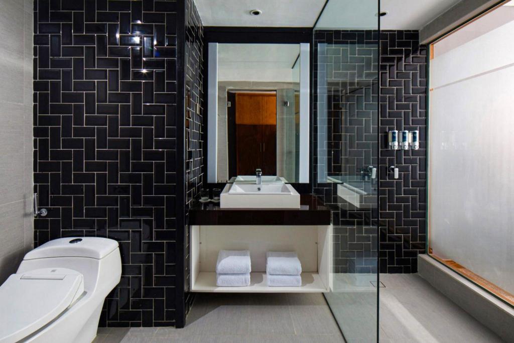 a bathroom with a sink and a toilet and a mirror at Four Points by Sheraton Balikpapan in Balikpapan