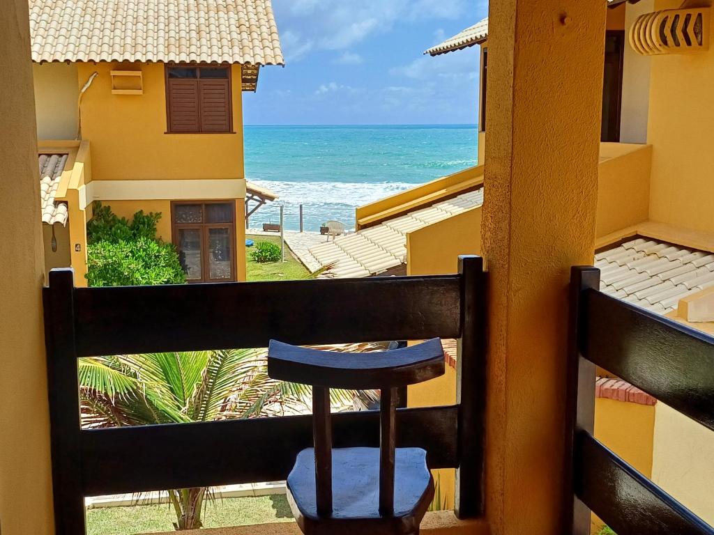 a stool on a balcony looking out at the ocean at Seu Refúgio à Beira-mar in Barra de São Miguel