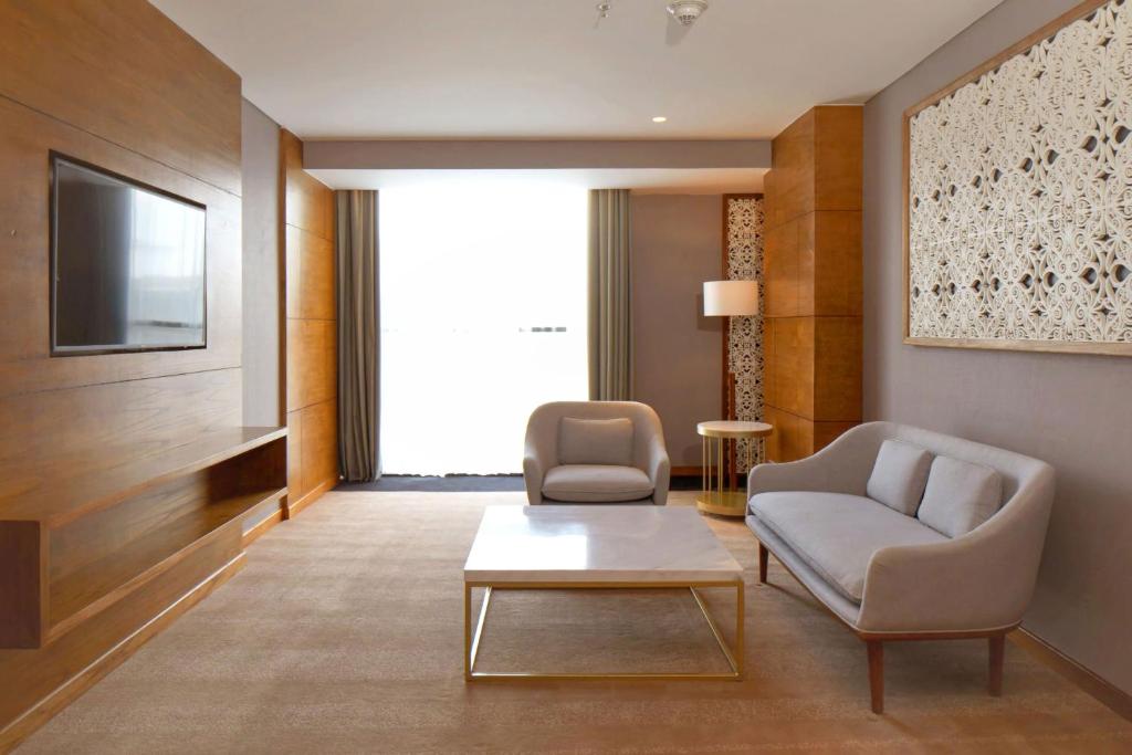 a living room with two chairs and a tv at Four Points by Sheraton Balikpapan in Balikpapan