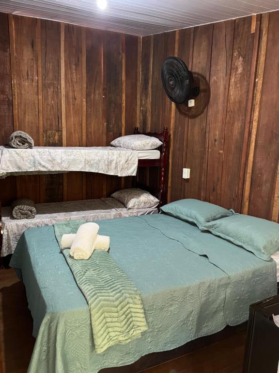 two beds in a room with wooden walls at Pousada Casa do Nilo in Ilha do Mel