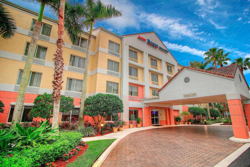 Un edificio de hotel con entrada de ladrillo y palmeras. en Fairfield Inn &amp; Suites By Marriott Jupiter, en Jupiter