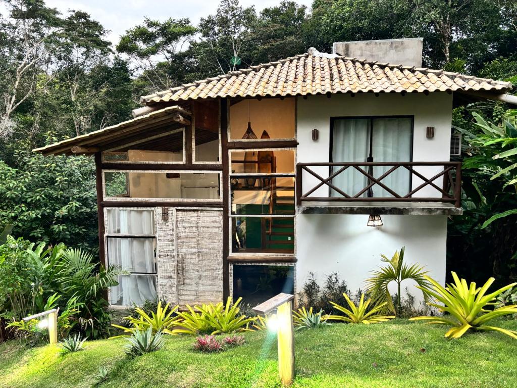 a small house with a balcony in a garden at Casa Recanto das arvores in Itacaré