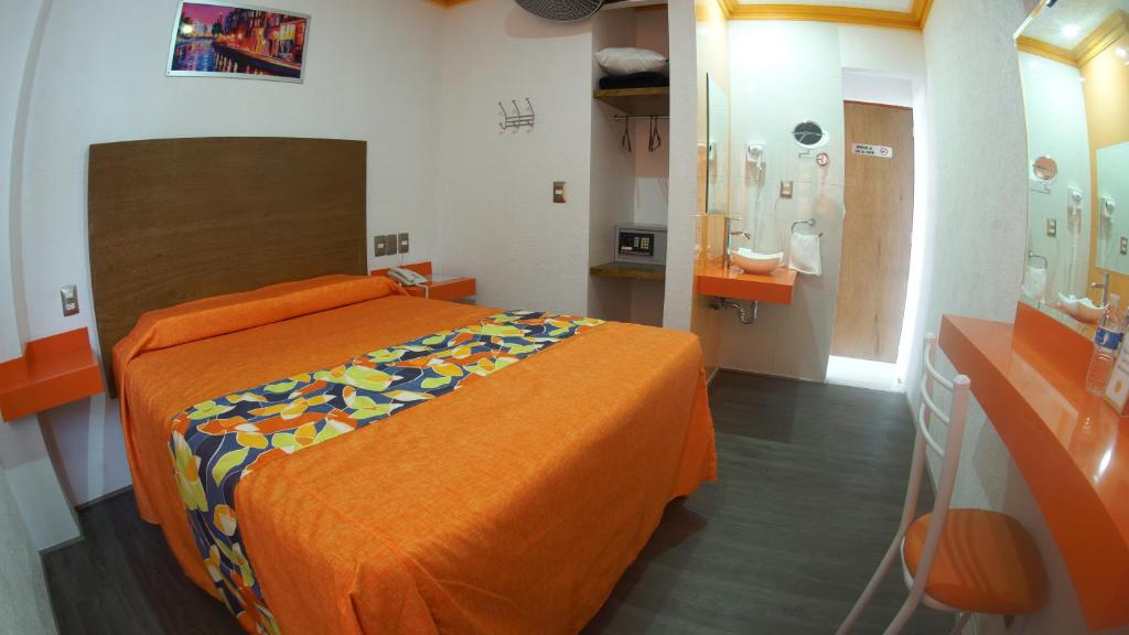 ein Schlafzimmer mit einem Bett mit einer orangefarbenen Tagesdecke in der Unterkunft Hotel Yekkan in Huauchinango