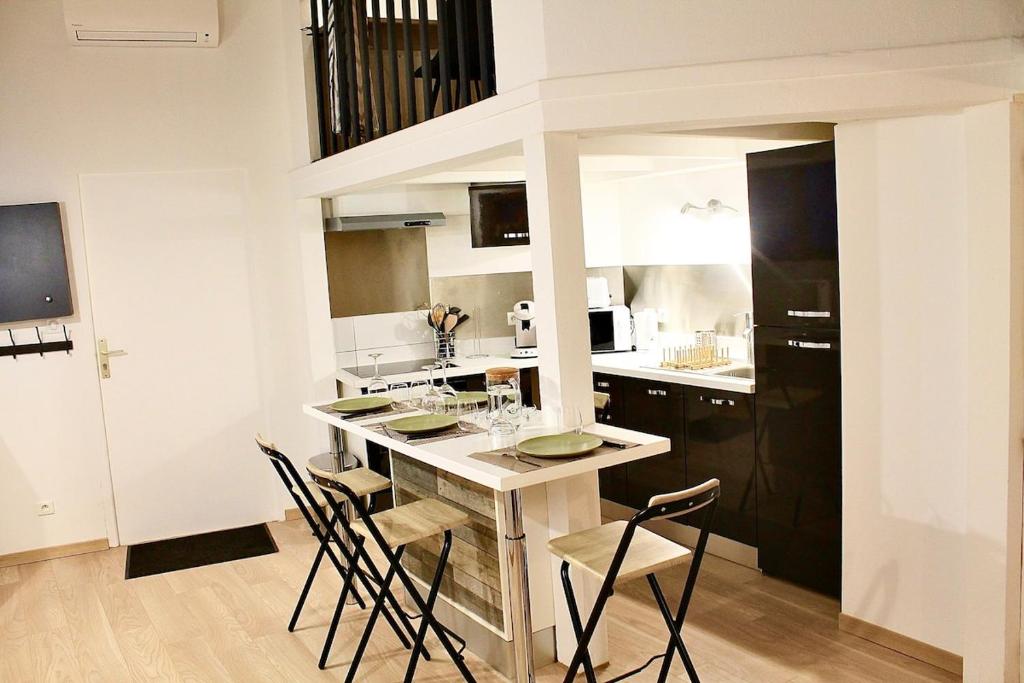 a kitchen with a counter with chairs in it at Appartement proche gare in Sélestat