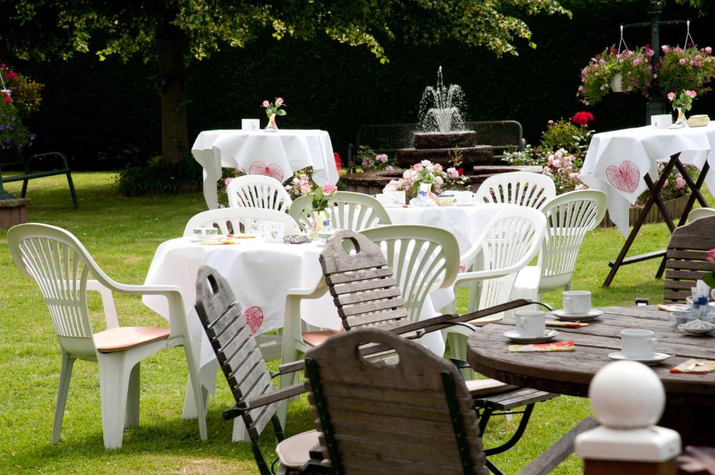 un groupe de tables avec des chaises blanches et une fontaine dans l'établissement Hotel Haus Mühlbach, à Nideggen