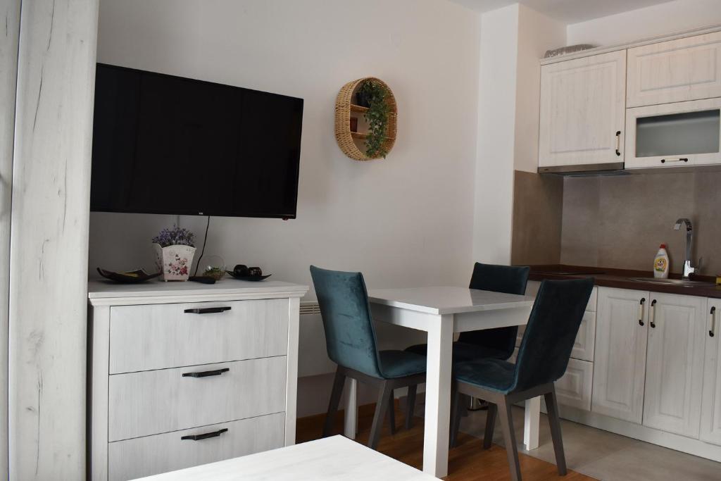 Una cocina con una mesa blanca y dos sillas azules. en Vila Irina Kopaonik - Apartman Jovana, en Kopaonik