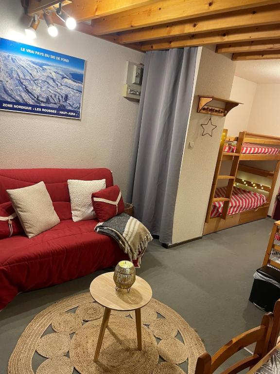 un salon avec un canapé rouge et une table dans l'établissement Chaleureux studio montagnard avec balcon 2402, à Prémanon