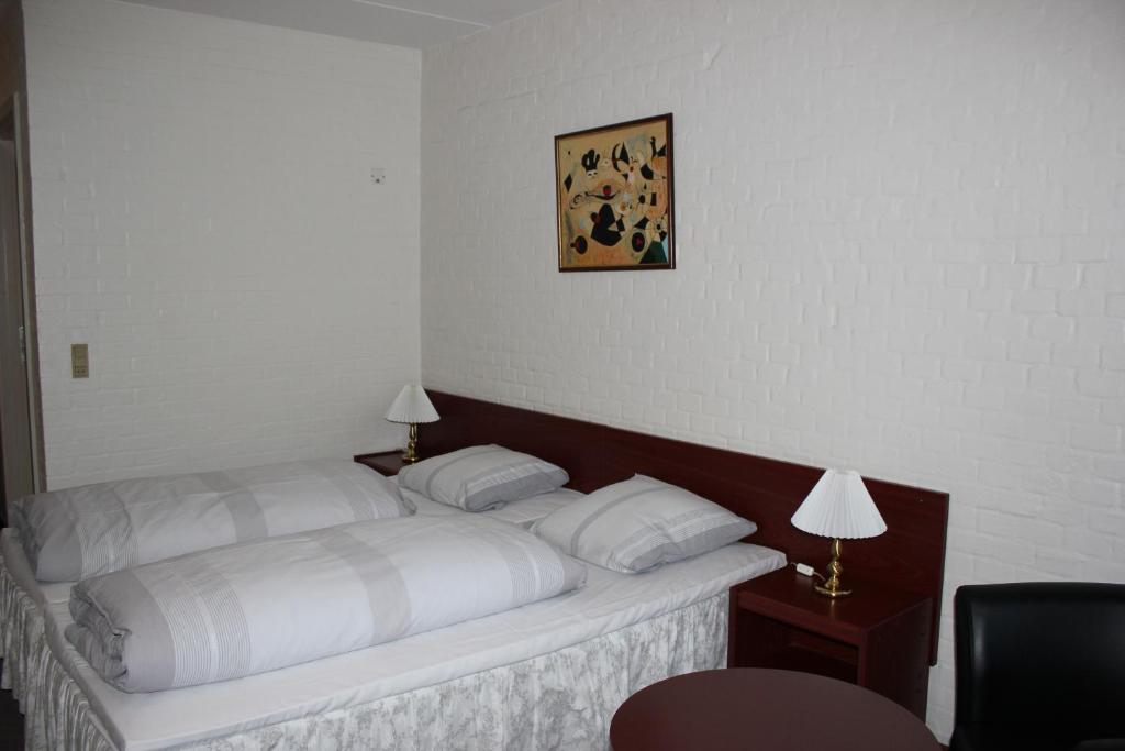 łóżko z białą pościelą i poduszkami w pokoju w obiekcie Sølyst Kro- Restaurant og Hotel I/S w mieście Aabenraa