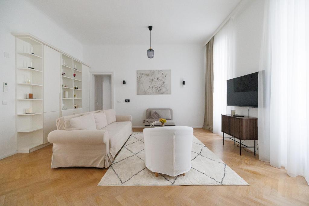 Una sala de estar con muebles blancos y un televisor. en Ultra Spacious 3-Bedroom 3-Bath Steps from Vienna's Historic Heart, en Viena