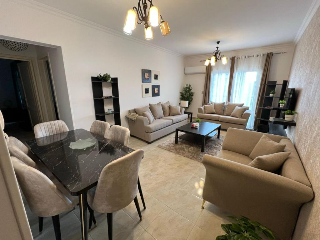 ein Wohnzimmer mit Tisch und Stühlen in der Unterkunft 2 bedroom apartment in rehab cityy in Burg el-Ḥudûd