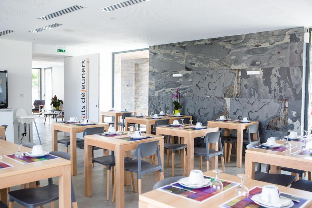 un restaurant avec des tables et des chaises en bois et un mur en pierre dans l'établissement Hotel Restaurant Santiago, à Hendaye