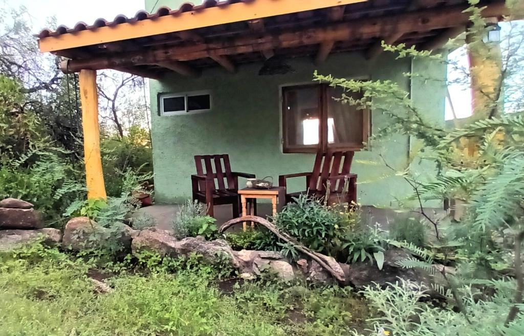 twee stoelen buiten een groen huis bij La calendula eco cabaña in Los Hornillos