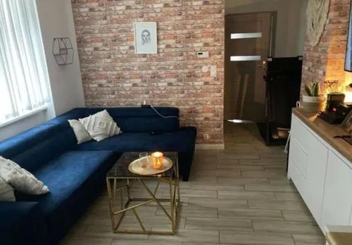 ein blaues Sofa im Wohnzimmer mit einem Tisch in der Unterkunft Apartament Szum Fal przy Plaży Międzyzdroje in Misdroy