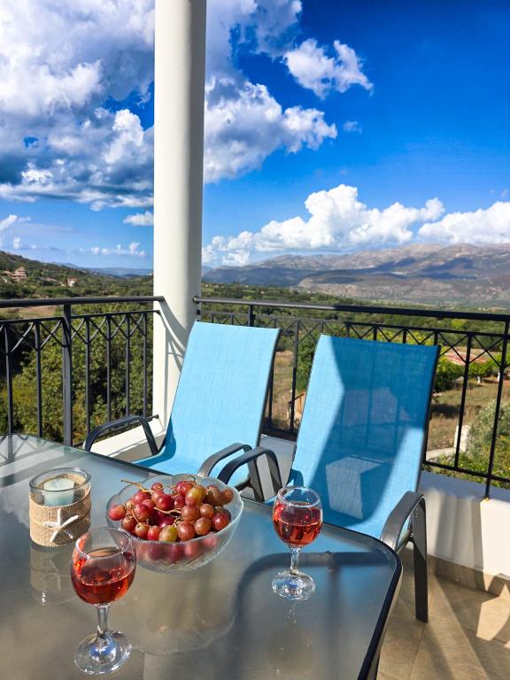a table with a bowl of tomatoes and two glasses of wine at Lakithra Apartments in Kefallonia