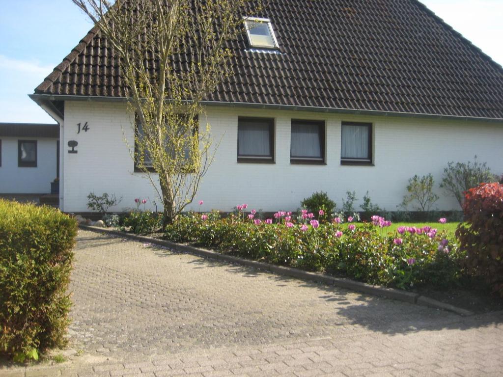 Uma casa branca com flores cor-de-rosa à frente. em Haus Buttgereit em Büsum