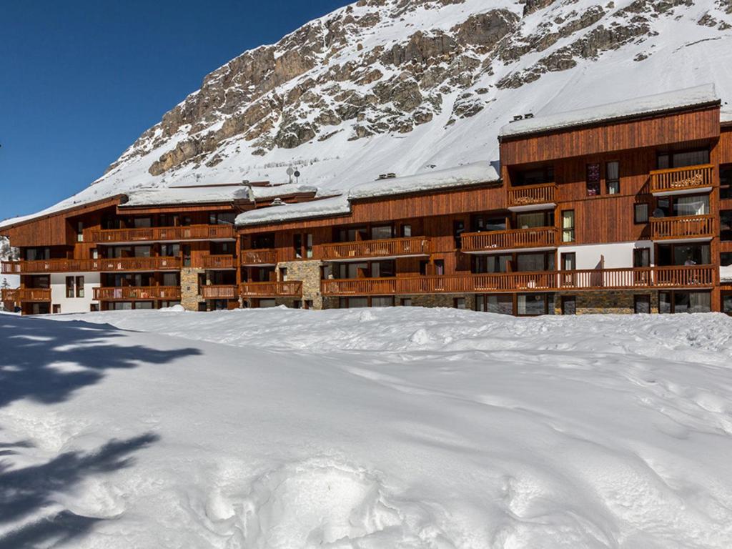 un bâtiment dans la neige devant une montagne dans l'établissement Appartement élégant avec cheminée et WIFI, 2 chambres - FR-1-694-376, à Val dʼIsère