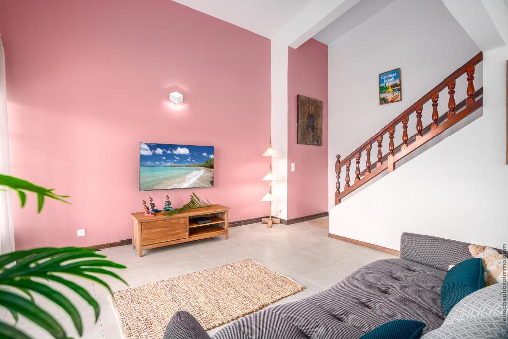 a living room with pink walls and a couch at Sublime Villa Piscine - Trésor de la Baie in La Trinité