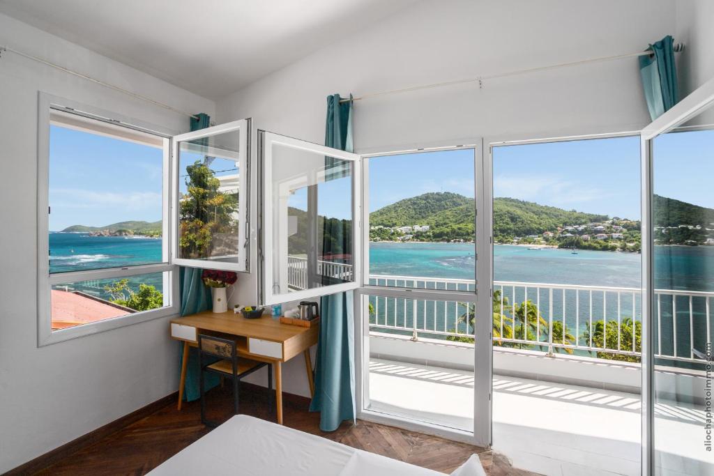 a room with windows and a desk with a view of the ocean at Sublime Villa Piscine - Trésor de la Baie in La Trinité