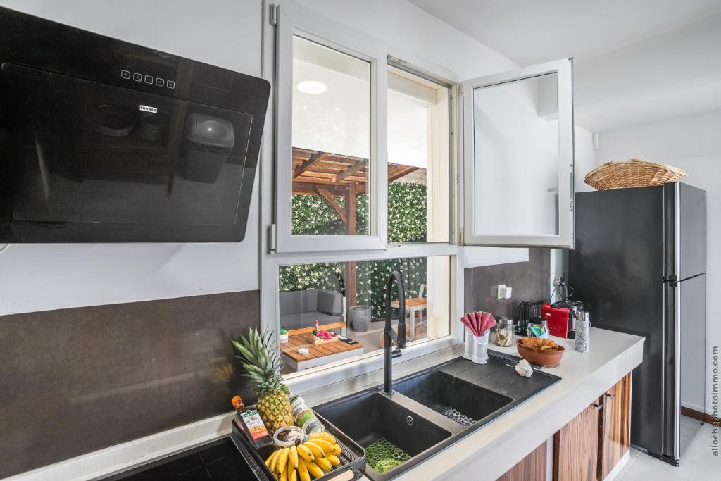 a kitchen with a sink and a microwave and a window at Sublime Villa Piscine - Trésor de la Baie in La Trinité