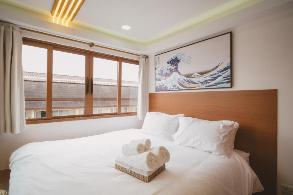 a bedroom with a white bed with a large window at Mini Jung Hayate in Chiang Mai