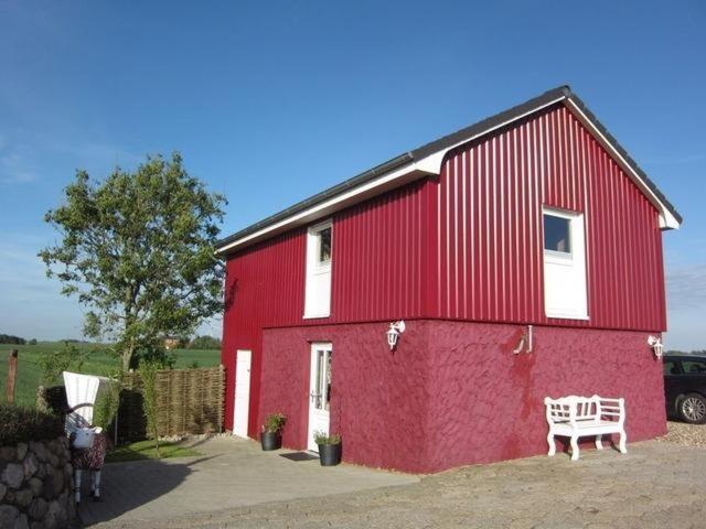un bâtiment rouge avec un banc devant dans l'établissement Nordlicht, à Hamburgerdeich