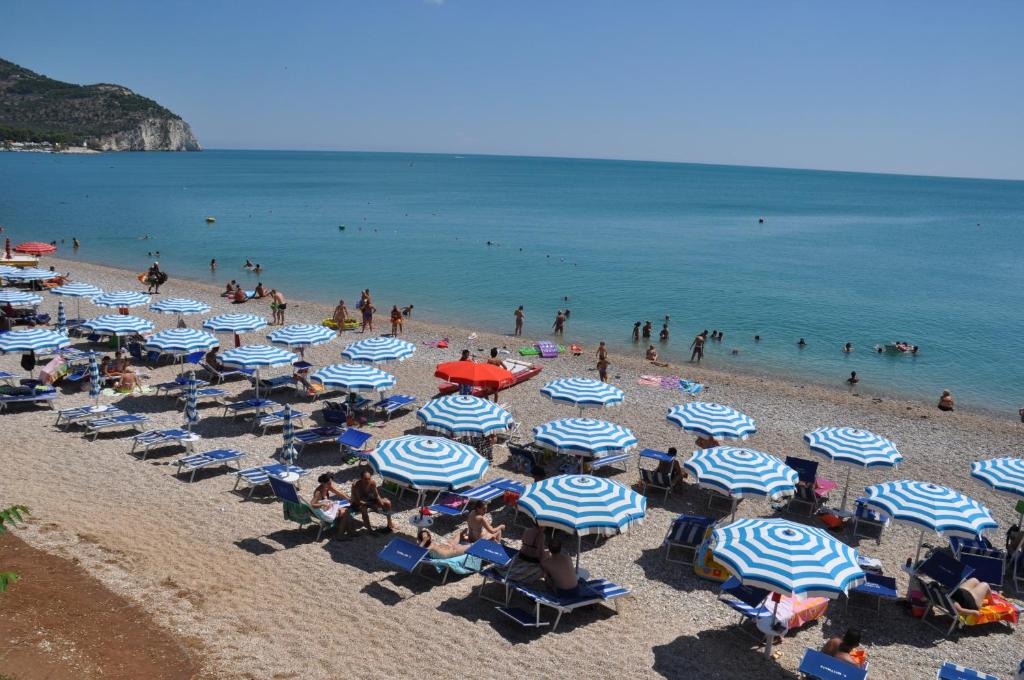 - une plage avec des parasols bleus et blancs dans l'établissement Mattinata Camping, à Mattinata