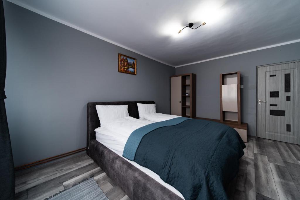 a bedroom with a large bed with a blue blanket at Szilárd Apartment in Miercurea-Ciuc