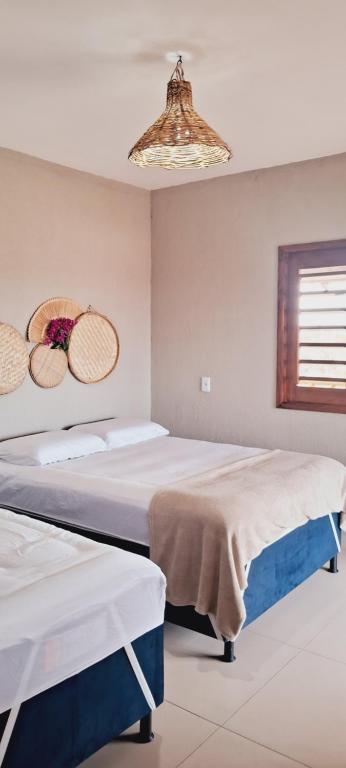 une chambre avec deux lits et un lustre dans l'établissement Chalé Sol de Macapá 2 - Refúgio Pertinho do Mar, à Luis Correia