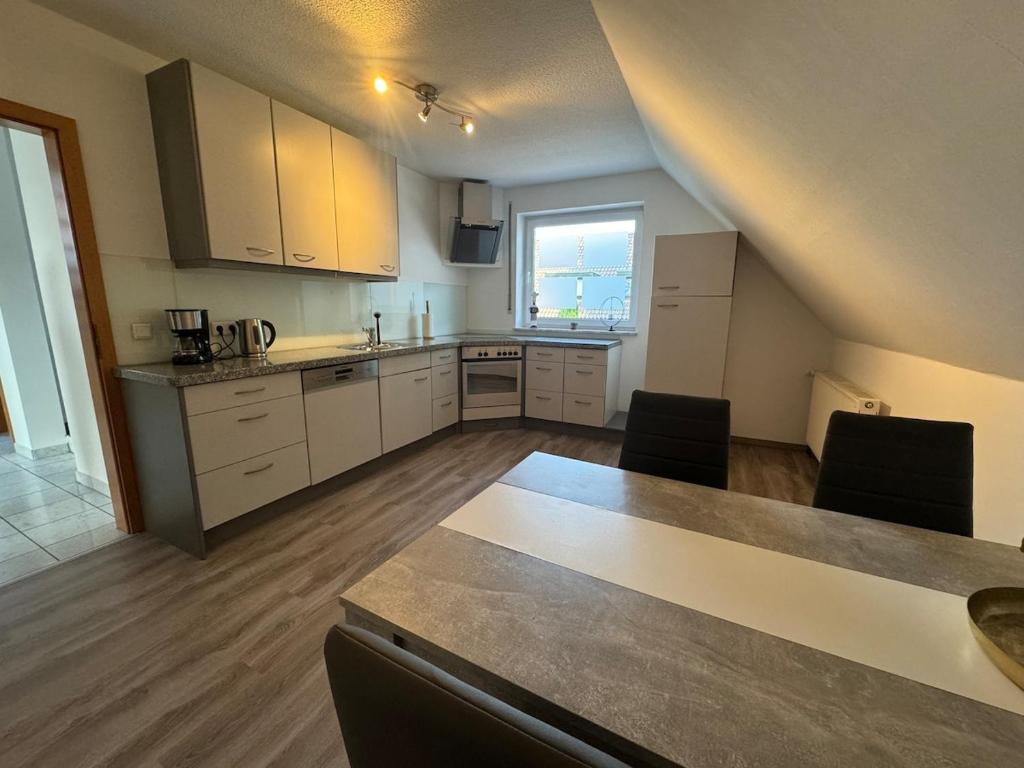 eine Küche mit weißen Schränken und einem Tisch mit Stühlen in der Unterkunft Ferienwohnung Steverding in Bocholt