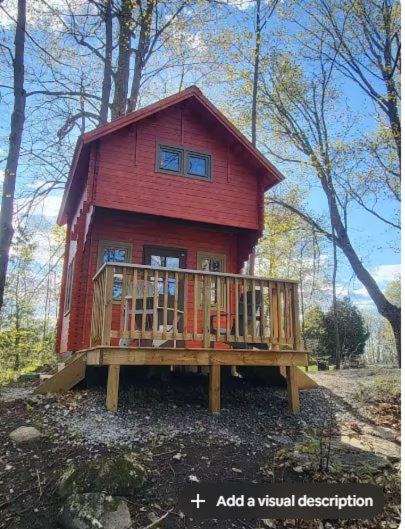 a red house with a deck in the woods at Shelley' Bay Bunkie 1 in Sharbot Lake