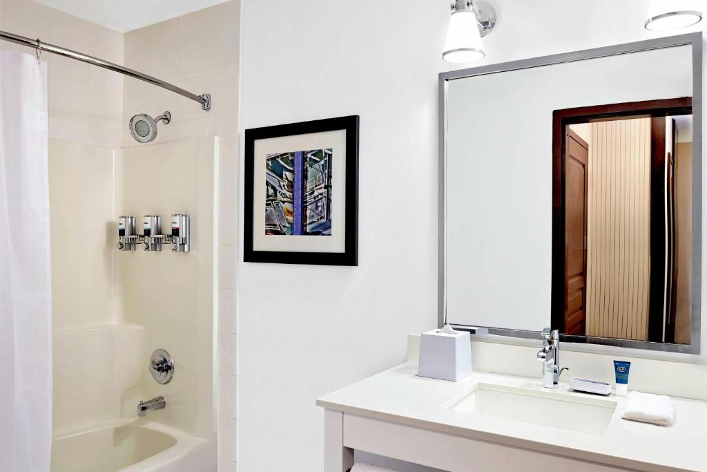 a white bathroom with a sink and a mirror at Four Points by Sheraton Surrey in Surrey