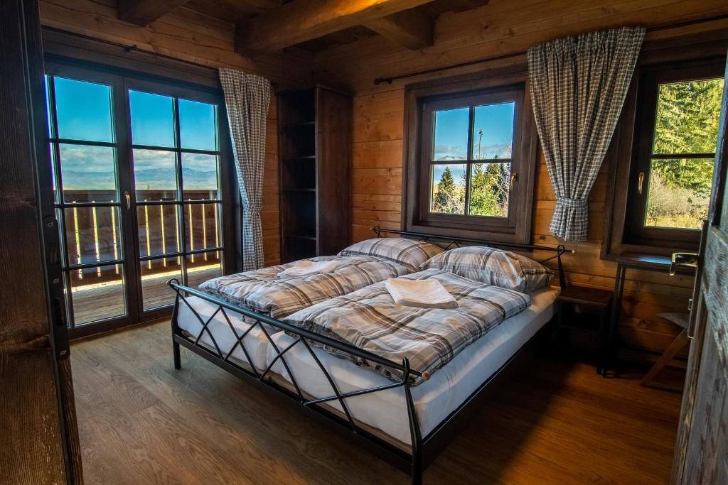 Un dormitorio con una cama en una habitación con ventanas. en Drevenica pod Zvonicou, en Demänovská Dolina