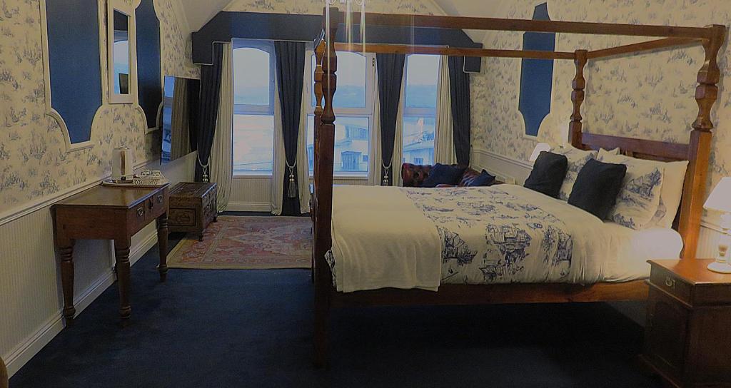 a bedroom with a canopy bed with a view of the ocean at Albany Lodge in Portrush