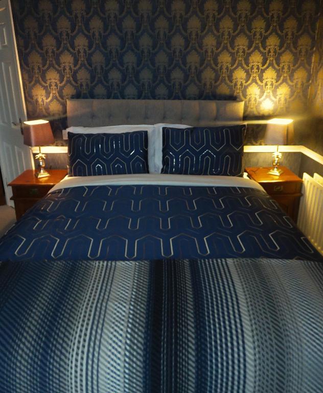 a blue bed in a bedroom with two lamps at Albany Lodge in Portrush