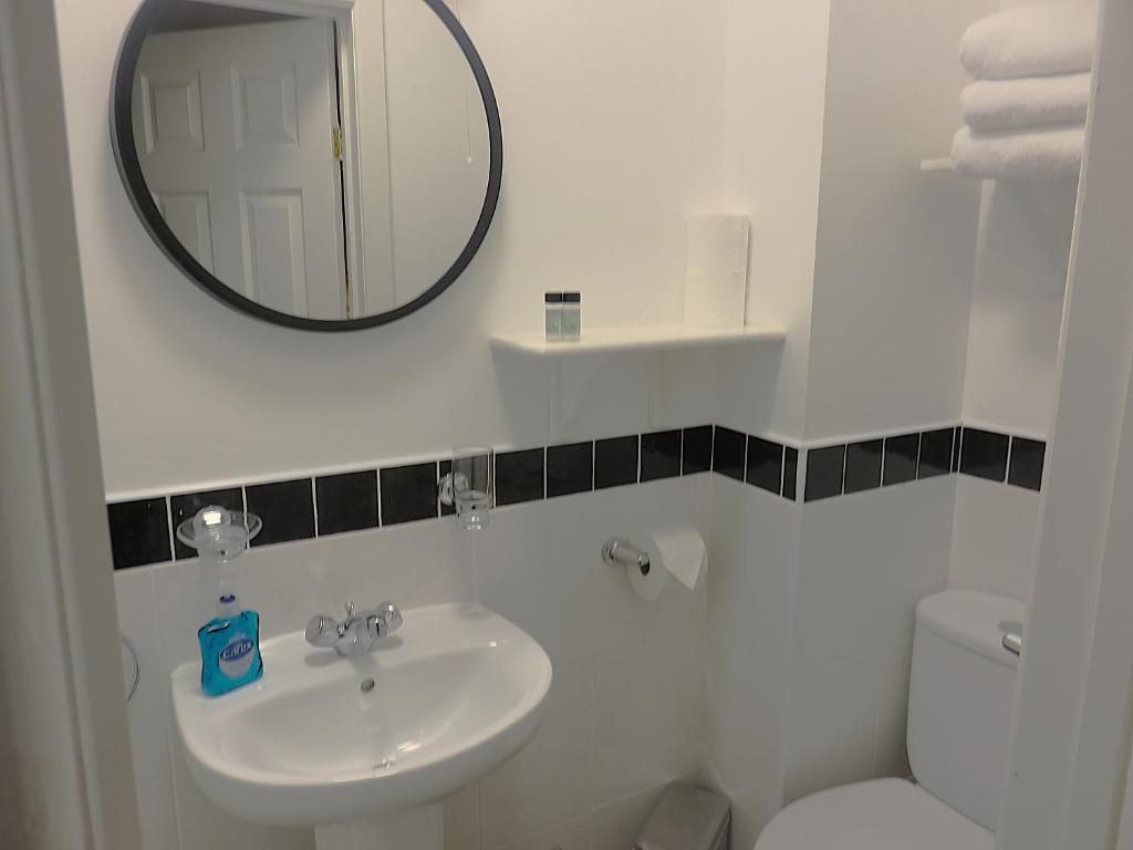 a white bathroom with a sink and a mirror at Albany Lodge in Portrush