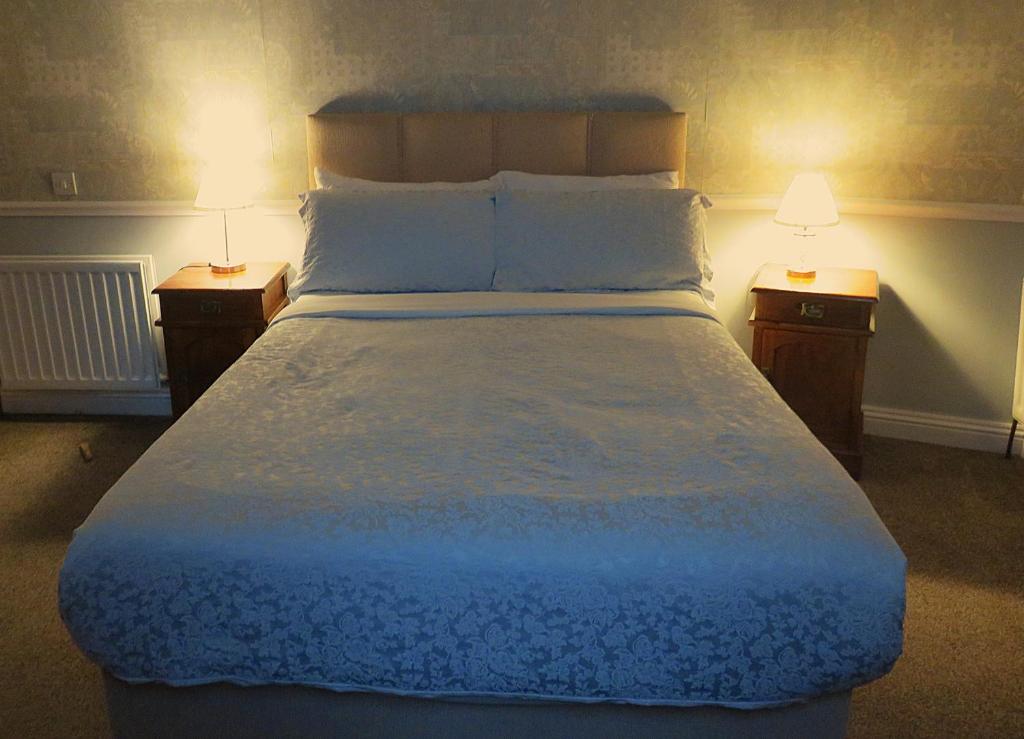 a bedroom with a large bed with two night stands at Albany Lodge in Portrush