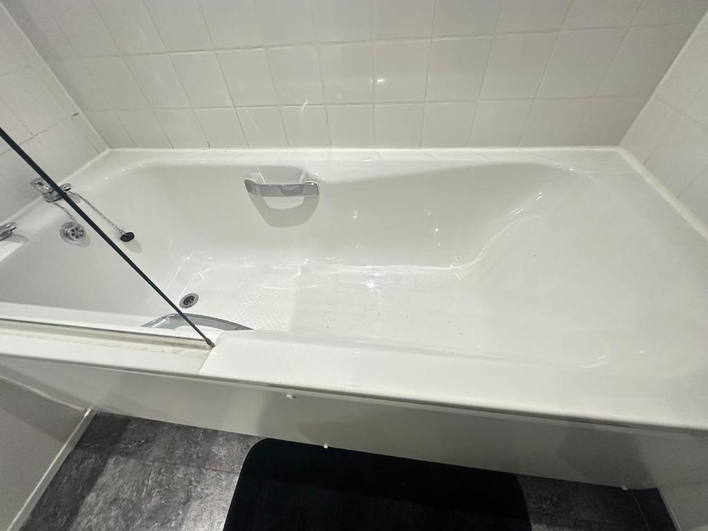 a white bath tub in a white tiled bathroom at Glasgow City Centre Stylish Flat in Glasgow