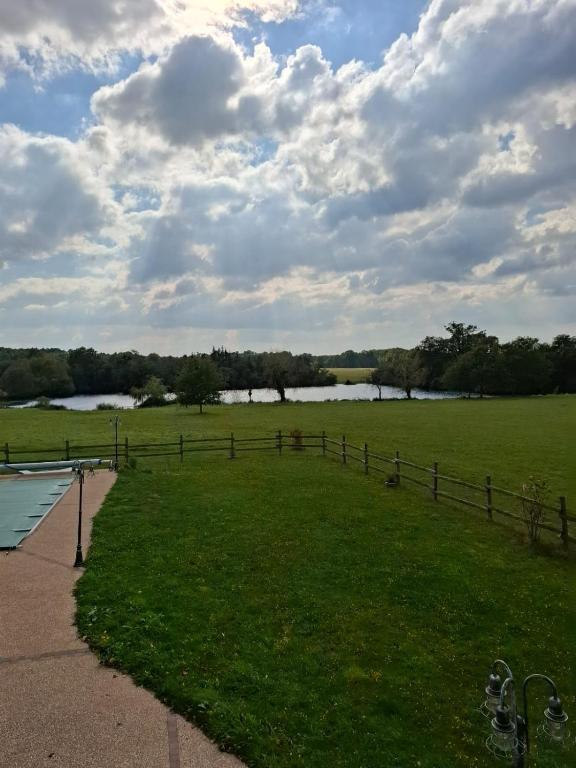 un champ herbeux avec une clôture et une masse d'eau dans l'établissement Maison de campagne, 17 couchages, à Tresson
