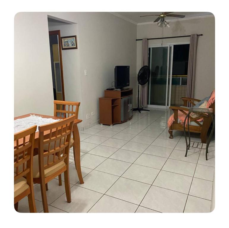 a living room with a table and chairs and a television at Apartamento aconchegante in Praia Grande